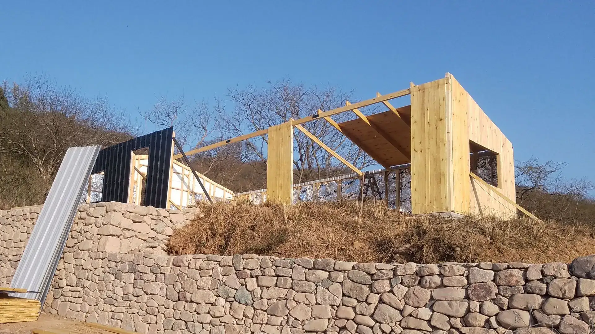 Estructura Wood Frame de una vivienda HOUSET en obra, sobre muro de piedra